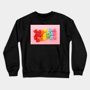 Heart-shaped multi-colored candy ordered in rainbow colors and shape on a pink background Crewneck Sweatshirt